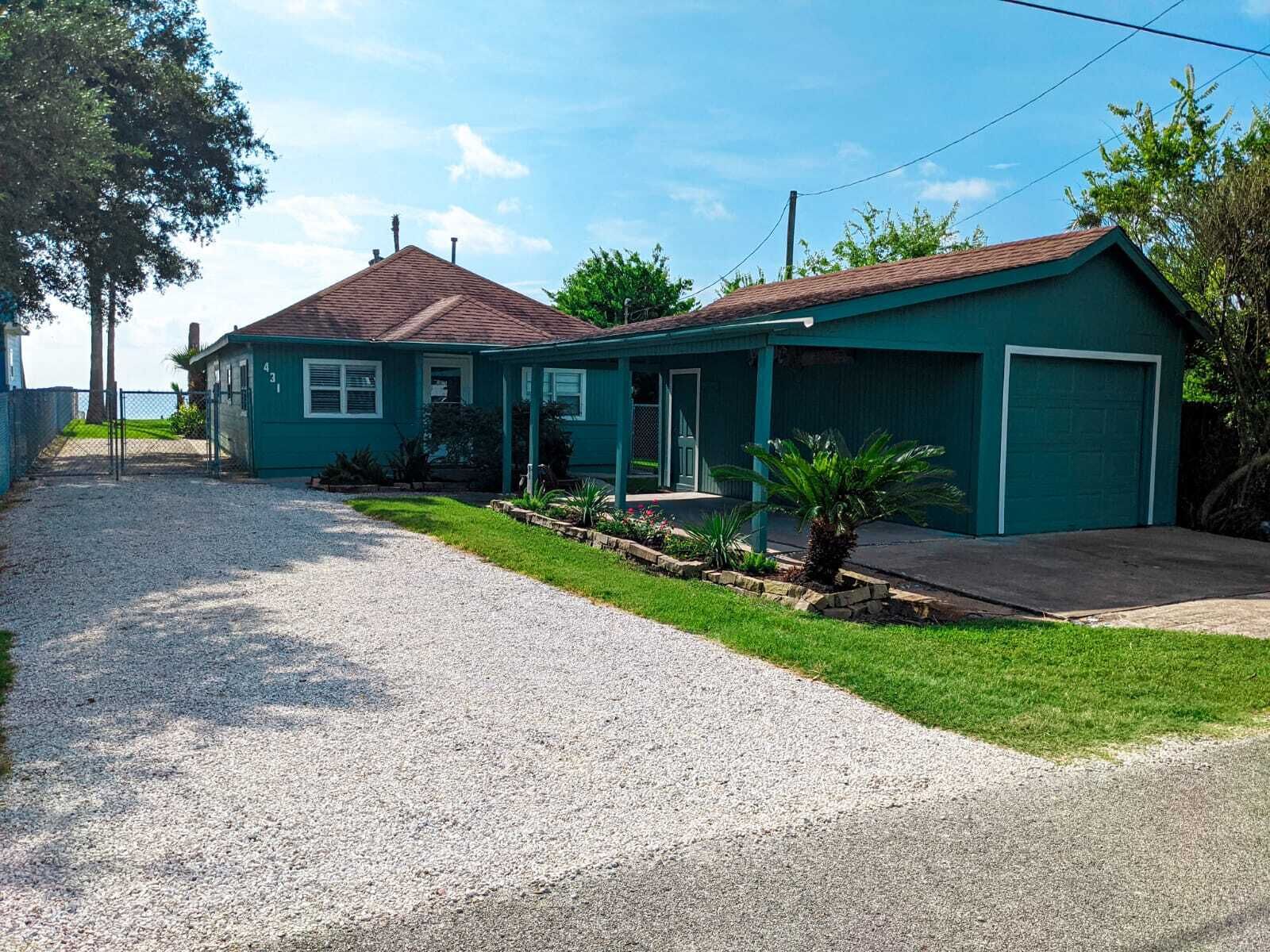 A single-story house with a gravel driveway, a front porch, and a garage.