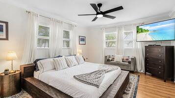 Une chambre à coucher avec un lit, une télévision, une commode et un ventilateur de plafond.