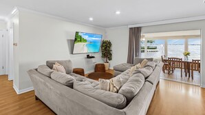 A modern living room with a large sofa, a flat-screen TV, a potted plant, and a view of the water. - Open Water Home with lots of dolphin and manatee sightings. Boat docking. (Ellenton)