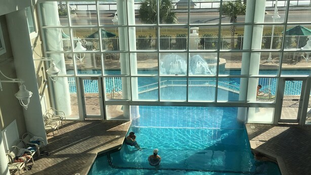 A pool area with clear views of the ocean through large windows.