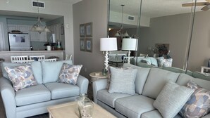 A living room with a light blue sofa, a beige coffee table, and a glass vase with seashells.