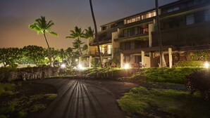 Un hotel de varios pisos con una entrada curva, palmeras y zonas exteriores bien iluminadas.