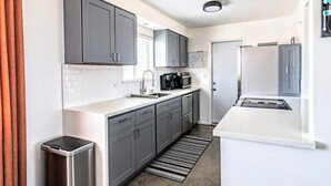 A modern kitchen with grey cabinets, a stainless steel sink, and a built-in oven. - Joshua Tree Getaway Private Desert Views (Yucca Valley)