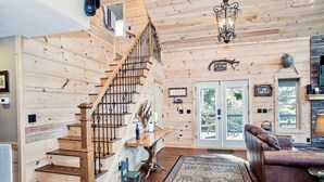 Un interior de madera con una escalera, un comedor y una zona de estar con un sofá de cuero.