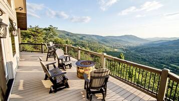 Une terrasse en bois avec des meubles d’extérieur, un foyer et une vue panoramique sur les montagnes.