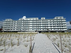 Un hôtel à plusieurs étages doté d’une cour intérieure, entourée de sable et d’une végétation clairsemée.