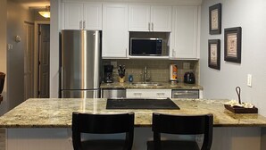 Una cocina moderna con armarios blancos, electrodomésticos de acero inoxidable y encimera de granito.