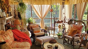 Un salon confortable avec un canapé, des fauteuils, une table basse et une grande fenêtre agrémentée de rideaux.