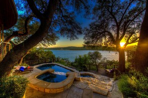 A pool area with hot tubs and a view of a lake at sunset. - Indulge in Luxury★Sweeping Lake Travis Views★Saltwater Pool★Mesmerizing Sunsets! (Volente)