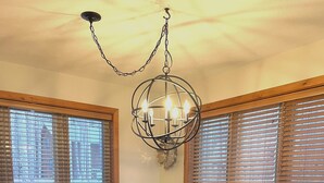 Un comedor con una mesa de madera y sillas negras, un cuenco decorativo sobre la mesa, y una lámpara colgante.