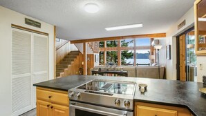 Une cuisine dotée d’un grand îlot central, de meubles en bois et offrant une vue sur l’extérieur.