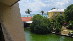 A view of a building with a red roof, surrounded by greenery and a body of water.