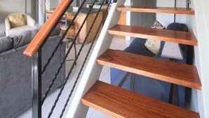 A modern staircase with wooden steps and a metal railing, leading to an upper floor.