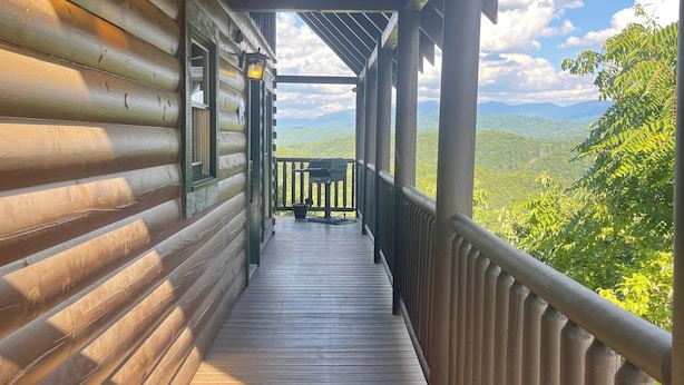 A wooden cabin with a covered porch and a view of the mountains.