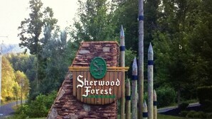 A sign for Sherwood Forest with a stone structure and a green emblem.