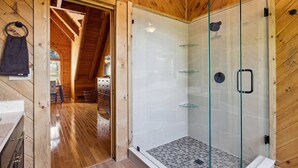 Un interior de fusta amb dutxa envidriada, sòl de fusta i zona de cuina a la vista.