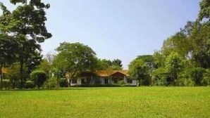 Una casa con techo rojo, rodeada por un campo verde y árboles.