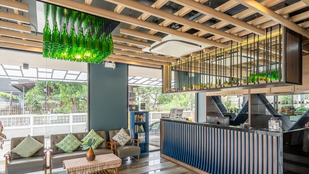 Een moderne lobby met een receptiebalie, een zithoek en een trap.