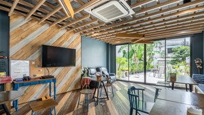Een modern interieur met een houten plafond, een flatscreen televisie, een zithoek met een bank en stoelen, en een groot raam met uitzicht op het omliggende landschap.