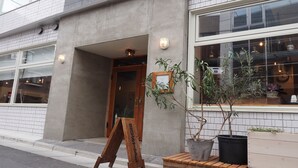 A building with a tiled facade, a wooden signboard, and potted plants near the entrance. - almond hostel & cafe Shibuya (Tokyo)