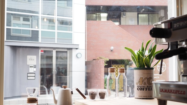A coffee shop counter with a coffee machine, a kettle, and various coffee beans and containers. - almond hostel & cafe Shibuya (Tokyo)