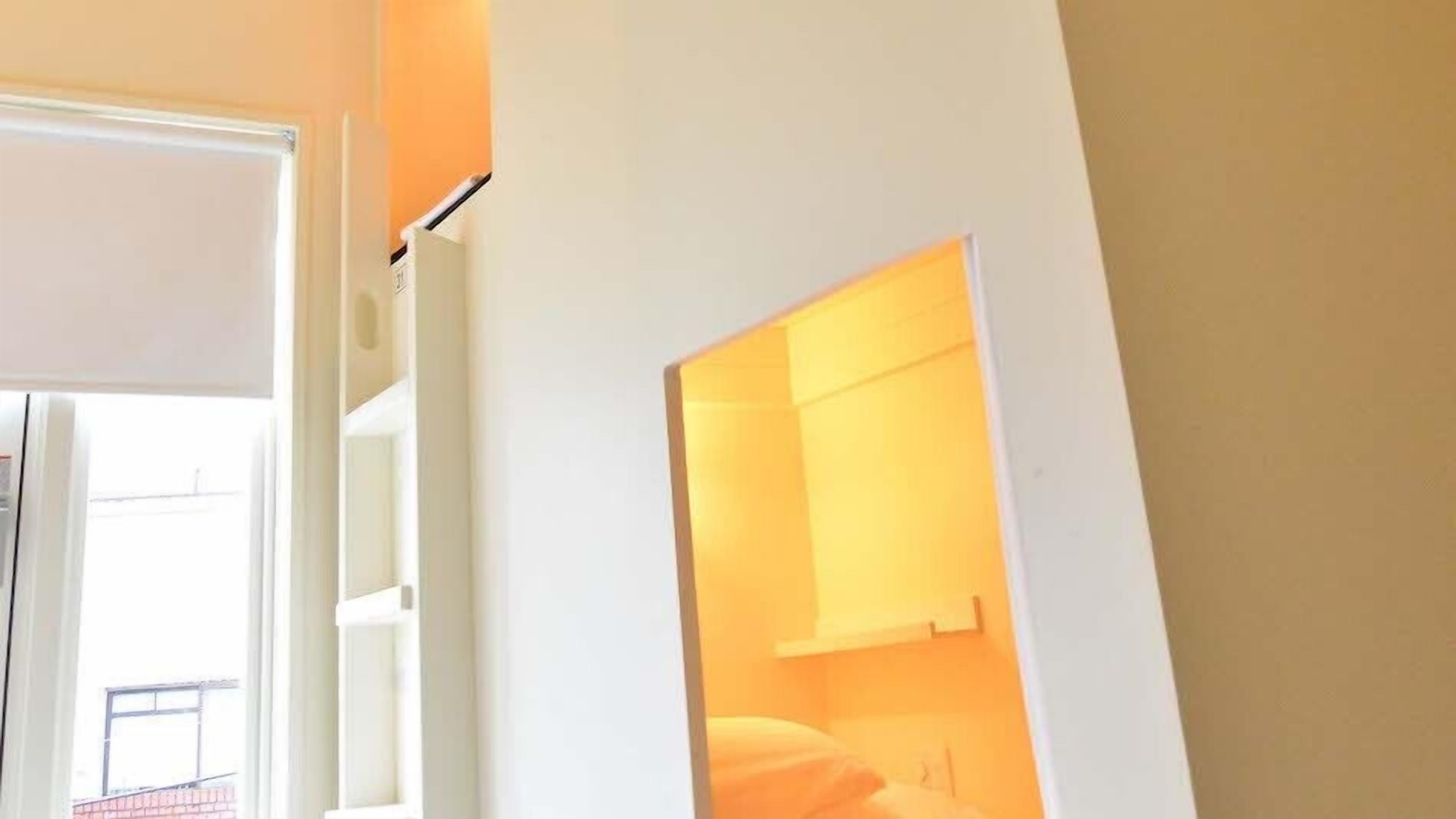Un couloir avec une porte donnant sur une pièce où se trouvent un lit et une table de chevet.