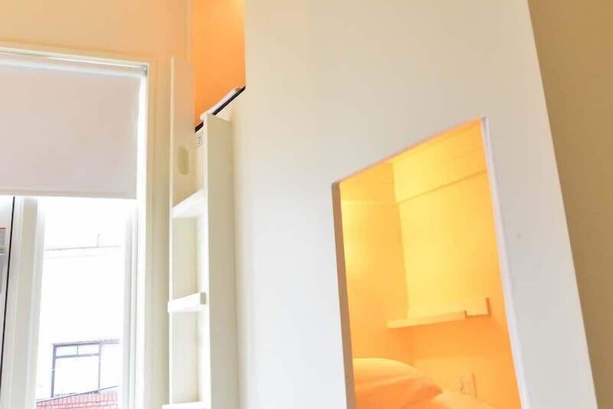 A hallway with a door leading to a room with a bed and a nightstand.