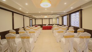 Une salle de conférence avec des rangées de chaises, une table centrale et de grandes fenêtres.