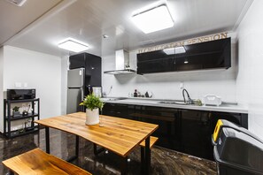 Una cocina moderna con armarios negros, una mesa de madera y un banco.