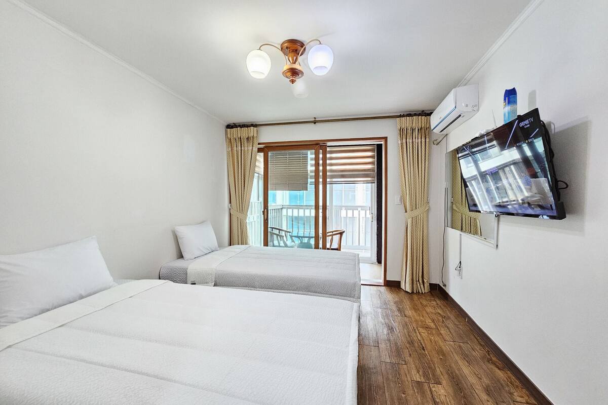 Une chambre d’hôtel avec deux lits, une télévision et un balcon équipé d’une chaise.