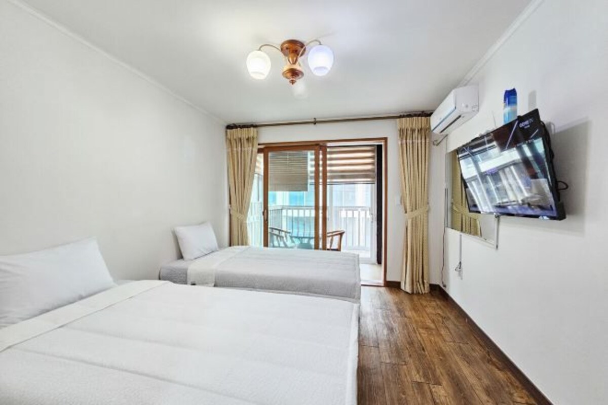 Een hotelkamer met twee bedden, een televisie, een airconditioner en een balkon met uitzicht.