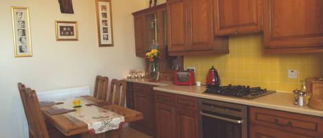 A kitchen with wooden cabinets, a dining table with chairs, a stove, and a toaster.