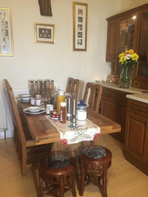 A dining area with a wooden table, chairs, and a vase of flowers. - Badjao Bed and Breakfast (Edinburgh)