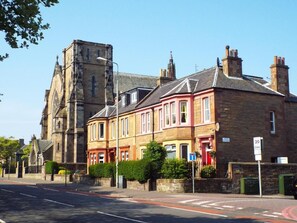 A street with historic stone buildings, a clear sky, and a speed limit sign. - Badjao Bed and Breakfast (Edinburgh)