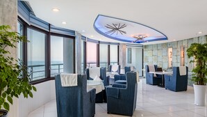 Ein stilvoller Lounge-Bereich mit Sitzgelegenheiten, großen Fenstern und einer dekorativen Decke.