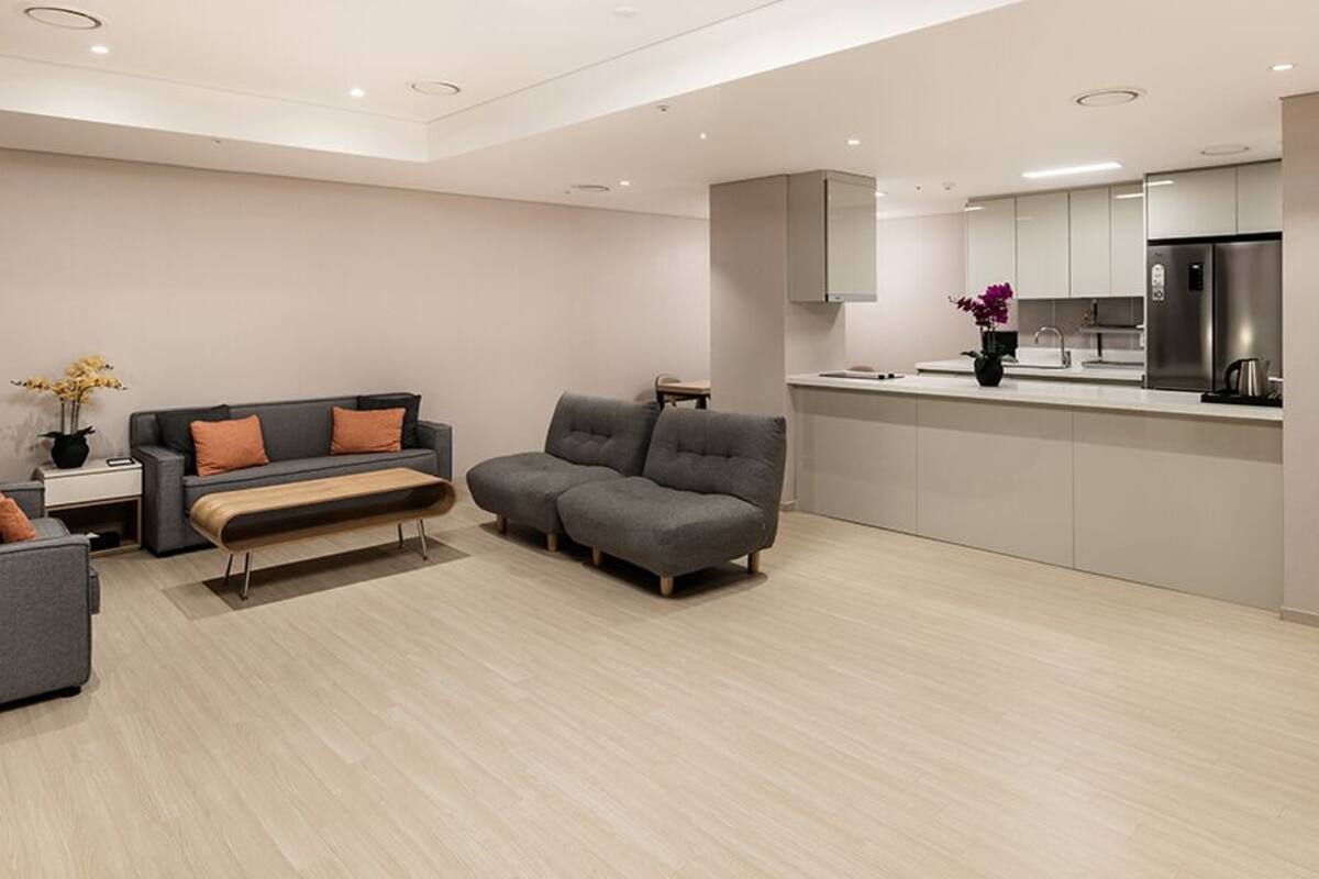 A modern living room with a grey sofa, a bench, and a small table with a vase of flowers.