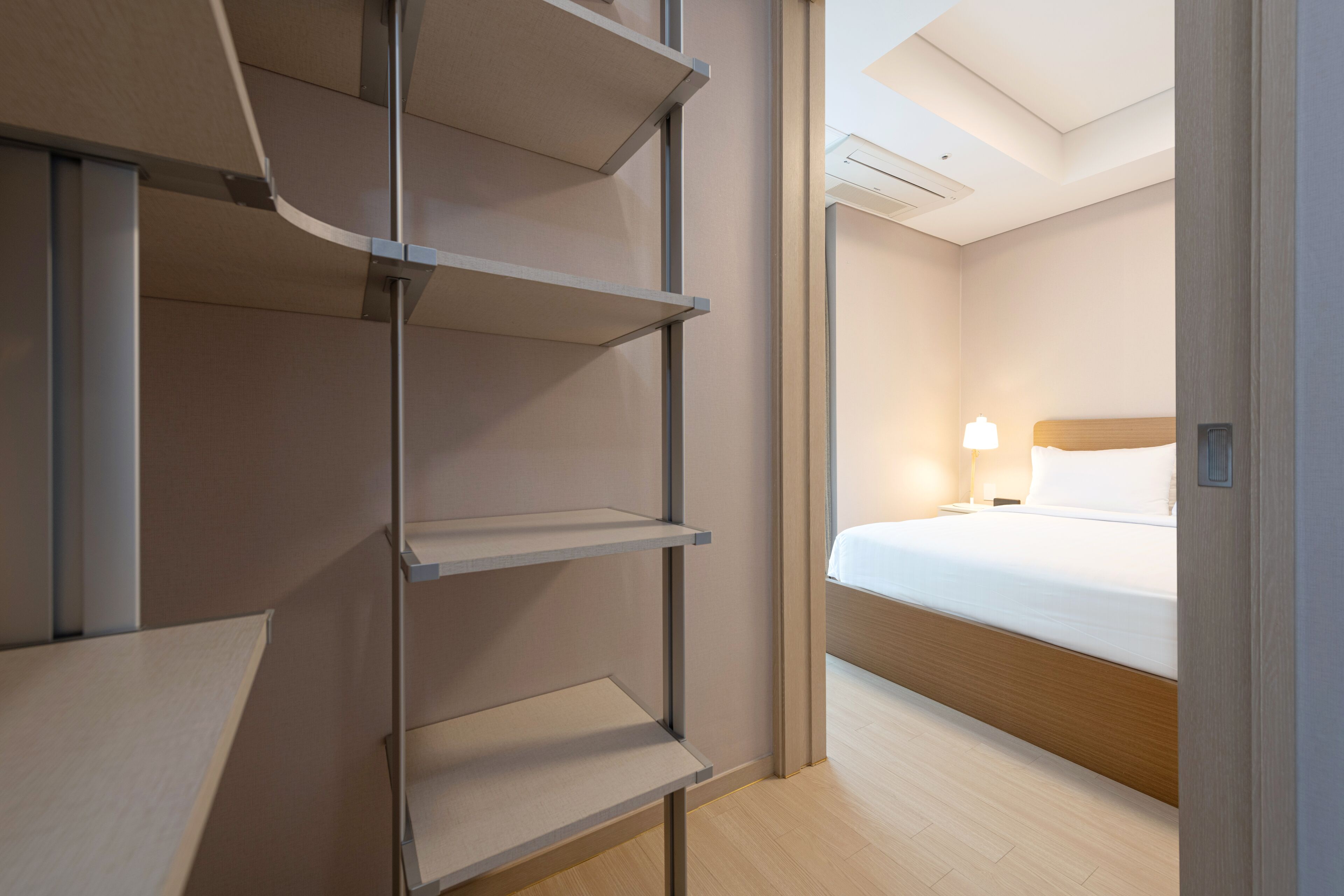 Una habitación de hotel con una cama, una mesita de noche y una unidad de almacenamiento empotrada.