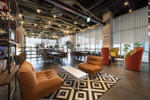Un intérieur moderne avec un espace salon central, des étagères et une grande fenêtre qui laisse entrer la lumière naturelle.