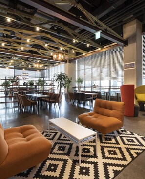 A modern interior with a central seating area, large windows, and a patterned rug. - Golden Tulip Incheon Airport Hotel & Suites (Incheon)