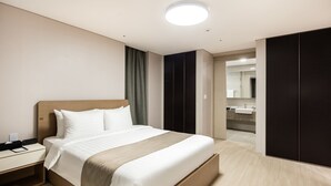 Una habitación de hotel moderna con una cama de madera, una mesita de noche, un espejo grande y un armario oscuro.