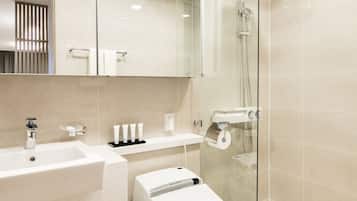 A modern bathroom with a glass-enclosed shower, a white sink, and a toilet.