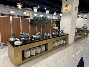 A buffet setup with multiple serving stations, stainless steel serving dishes, and a variety of utensils. - Golden Tulip Incheon Airport Hotel & Suites (Incheon)