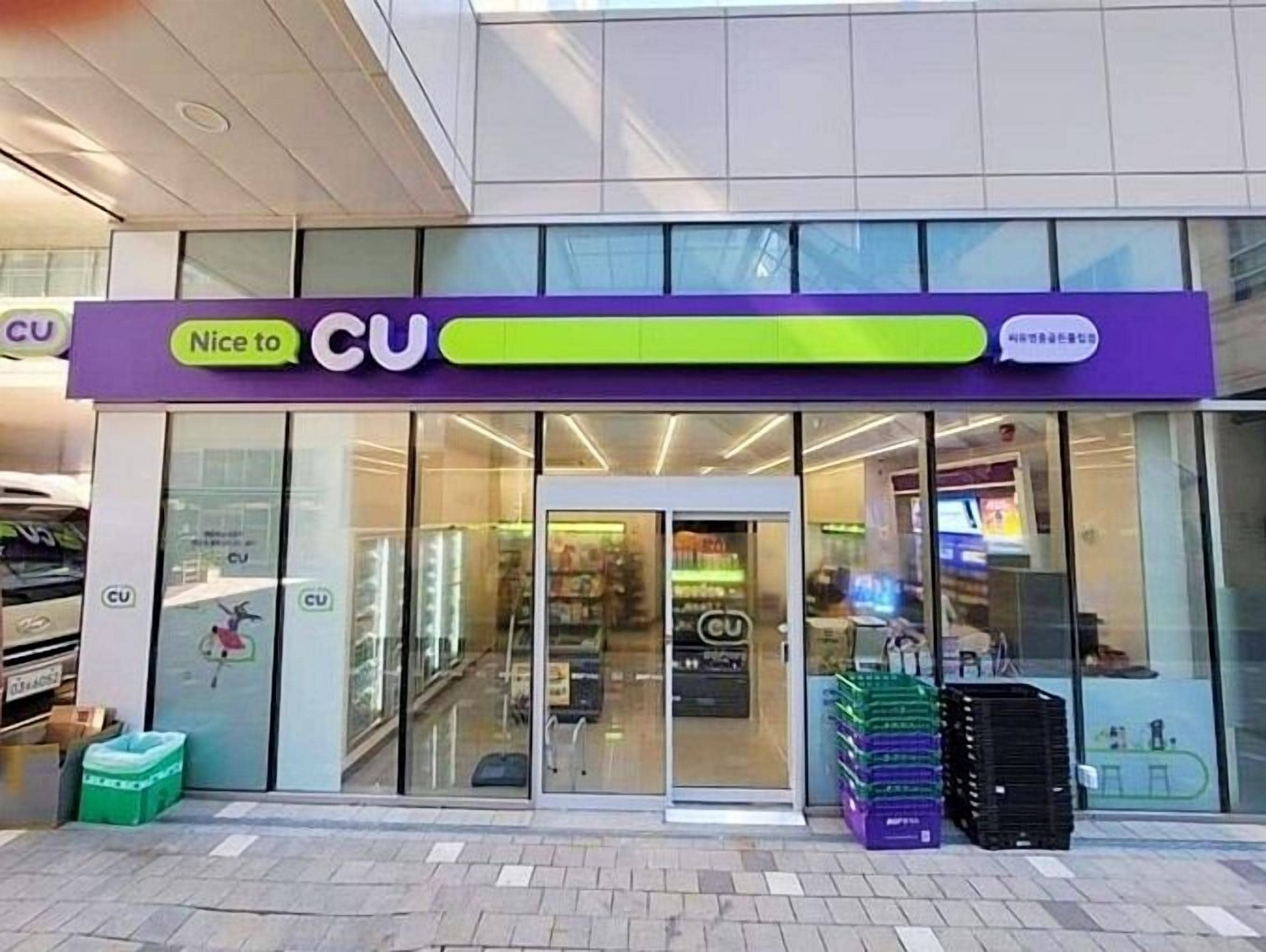 A CU store with a purple and green sign, glass doors, and a visible interior with shelves and products.