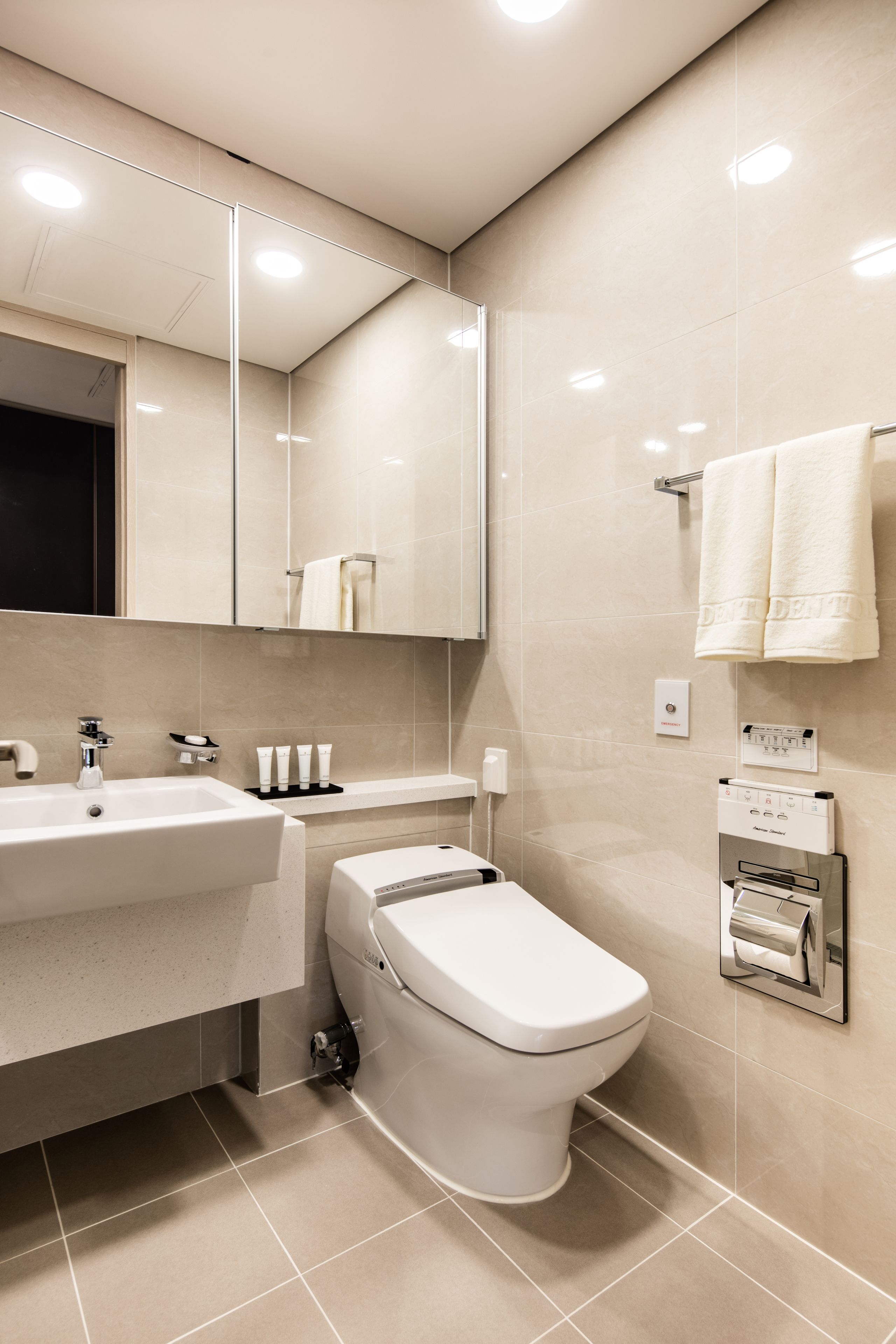 A modern bathroom with a white sink, mirror, and toilet.