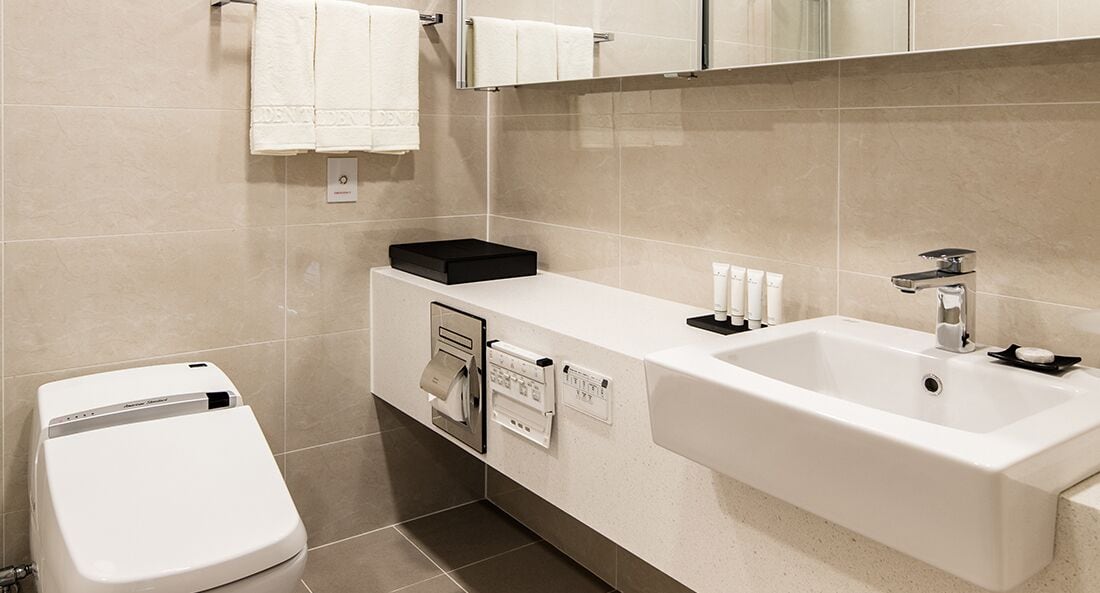 A modern bathroom with a white toilet, a sink with a mirror, and a towel rack.