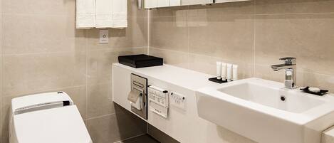 Un baño moderno con inodoro blanco, lavamanos con espejo y un perchero para toallas.