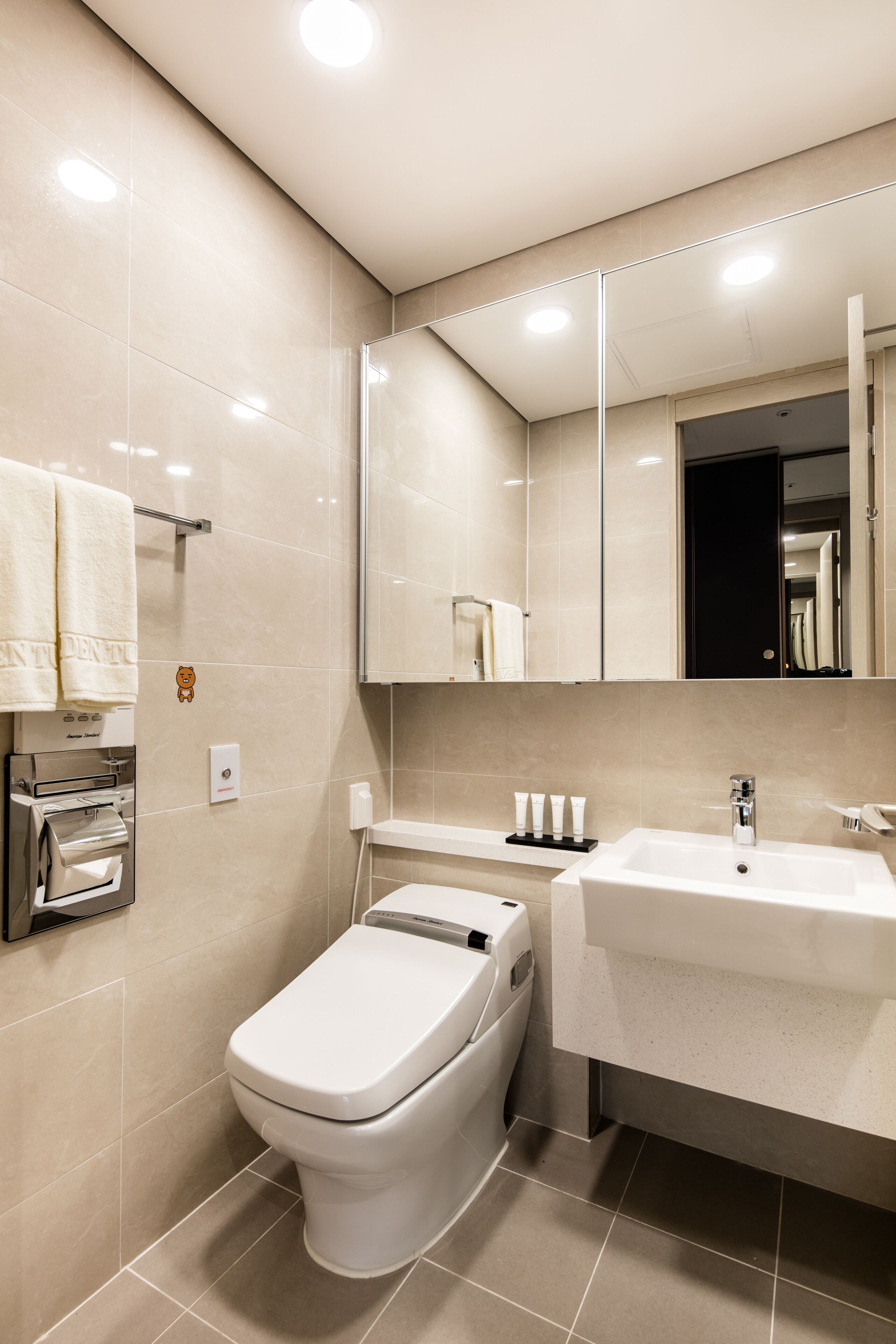 Un baño moderno con inodoro, lavamanos y espejo.