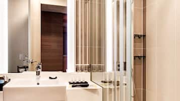 Un bagno moderno con un lavandino grande, box doccia in vetro e una parete decorativa in legno.