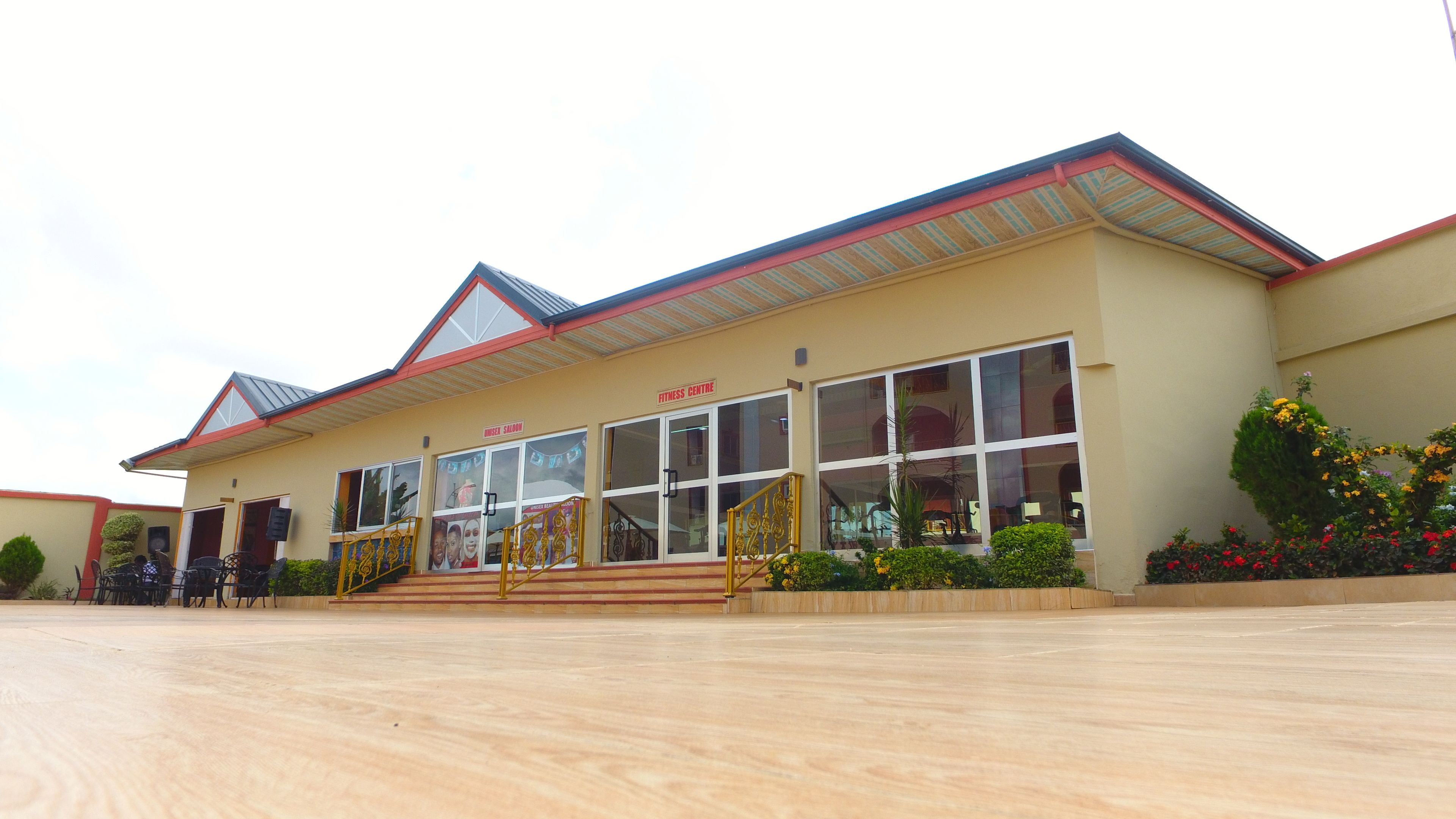 A fitness centre with a large glass facade, a red roof, and a staircase leading to the entrance.