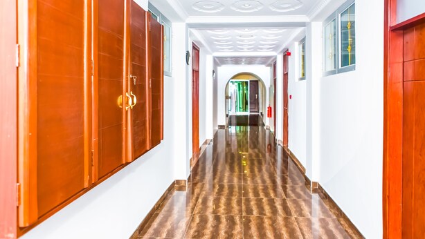 A hallway with a polished floor and wooden doors. - Cofkans Hotel (Obuasi)